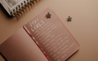 Top view of a 2021 goals notebook with handwritten list and star decorations, ideal for planning inspiration.