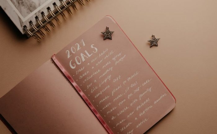 Top view of a 2021 goals notebook with handwritten list and star decorations, ideal for planning inspiration.