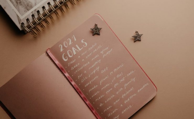 Top view of a 2021 goals notebook with handwritten list and star decorations, ideal for planning inspiration.